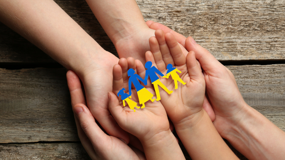 Drei Paar geöffnete Hänge liegen ineinander. In den obersten Handflächen liegen Figuren in den Farben der ukrainischen Flagge. (Quelle: stock.adobe.com | Olga Yastremska, New Africa) Drei Paar geöffnete Hänge liegen ineinander. In den obersten Handflächen liegen Figuren in den Farben der ukrainischen Flagge.