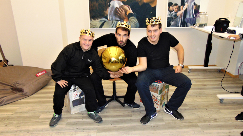 Drei Männer haben eine goldene Krone auf dem Kopf und zusammen eine goldene Kugel in der Hand