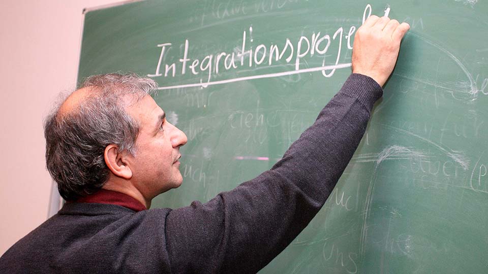 Ein Mann schreibt das Wort: Integrationsprojekte an eine Tafel