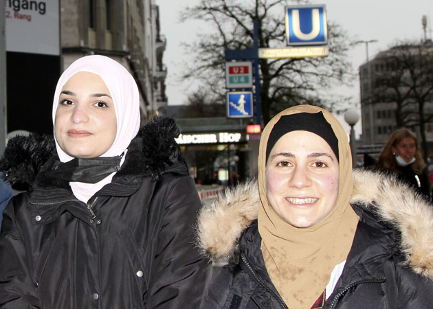 Zwei junge Frauen stehen nebeneinander auf der Straße und lächeln in die Kamera.