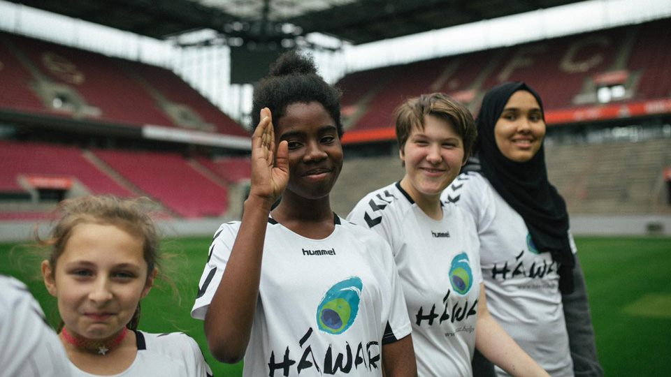 Vier junge Mädchen stehen in einem Fussballstadion