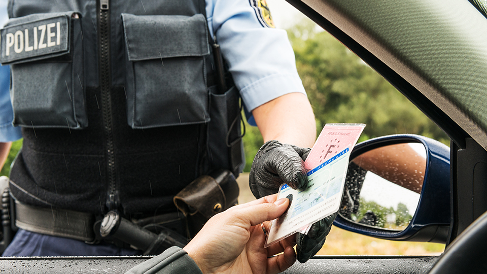 Ein Polizist nimmt von einer Person Ausweisdokumente entgegen.
