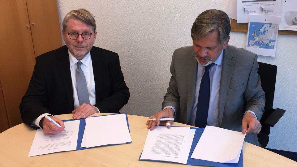 Zwei Männer sitzen an einem Tisch. Vor ihnen liegen Dokumente. (Quelle: BAMF | Lorenz) Zwei Männer sitzen an einem Tisch. Vor ihnen liegen Dokumente.