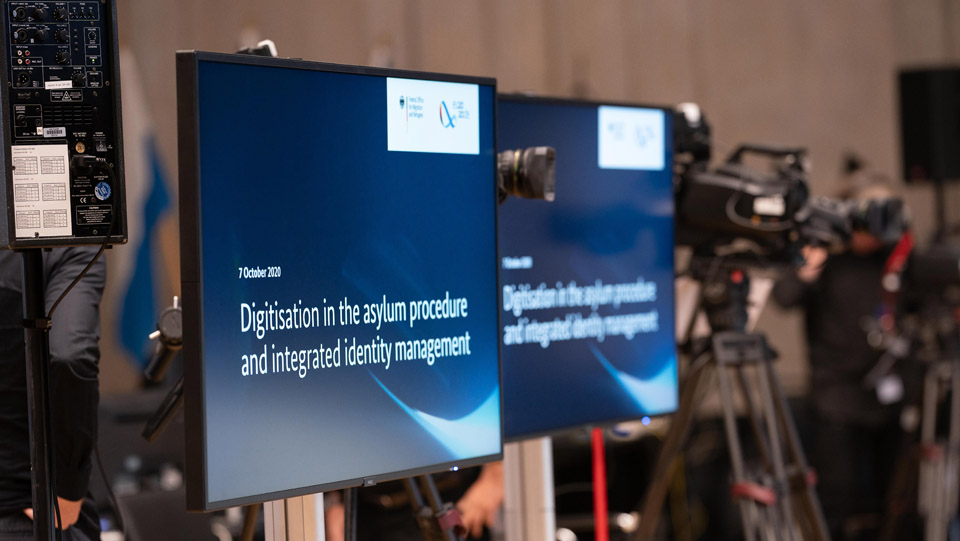 Zwei Bildschirme zeigen das Thema der Konferenz in englischer Sprache (Quelle: BAMF) Zwei Bildschirme zeigen das Thema der Konferenz in englischer Sprache