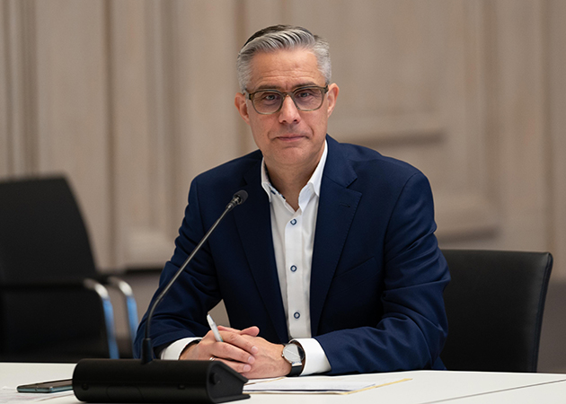 Ein Mann sitzt vor einem Mikrofon und guckt in die Kamera. (Quelle: © BAMF) Ein Mann sitzt vor einem Mikrofon und guckt in die Kamera.