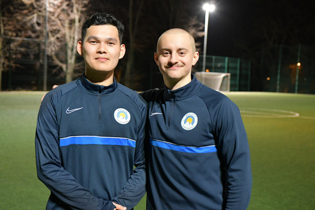 Zwei junge Männer porträtieren auf einem Sportplatz (Quelle: © BAMF | Kristin Kasten) Zwei junge Männer porträtieren auf einem Sportplatz