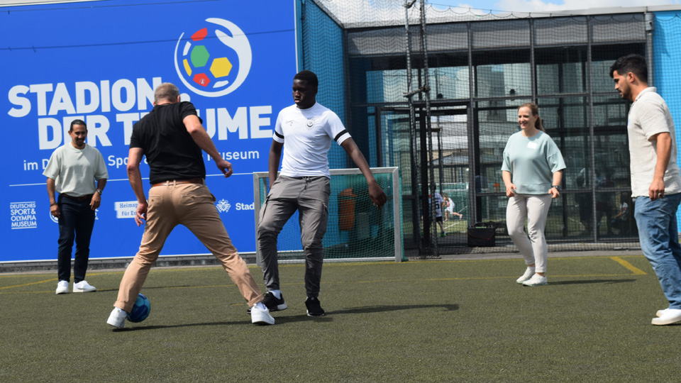 Fünf Personen spielen Fussball. (Quelle: BAMF | Anke Lübbert) Fünf Personen spielen Fussball.