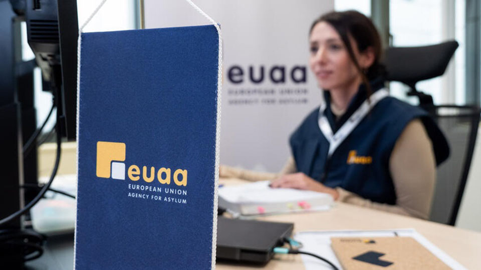 Eine Frau sitzt an einem Schreibtisch. (Quelle: © European Union Agency for Asylum 2025) Eine Frau sitzt an einem Schreibtisch.