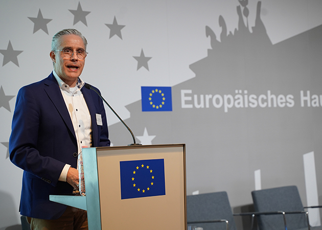 Ein Mann hält eine Rede vor einem Publikum. (Quelle: © BAMF) Ein Mann hält eine Rede vor einem Publikum.