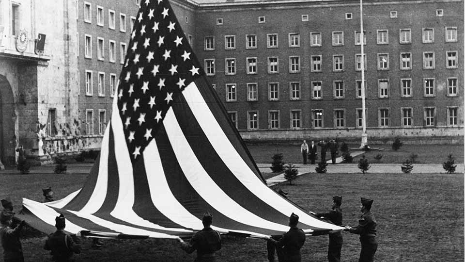 Mehrere Soldaten stehen auf einem Platz und hissen eine Flagge. (Source: BAMF) Mehrere Soldaten stehen auf einem Platz und hissen eine Flagge.