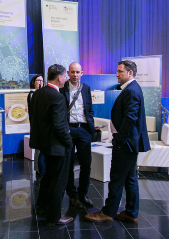 Drei Männer unterhalten sich auf einem Messestand (Quelle: © Toby Giessen) Drei Männer unterhalten sich auf einem Messestand