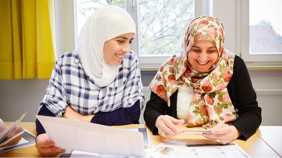 Zwei Frauen sitzen mit Unterlagen an einem Tisch