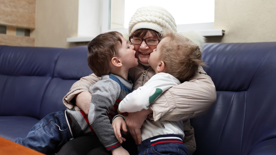 Eine Frau umarmt zwei kleine Kinder (Source: © iStock|Radist) Eine Frau umarmt zwei kleine Kinder