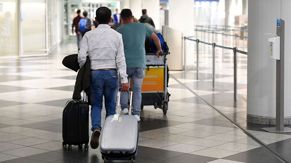 Menschen laufen durch eine Flughafenhalle (Quelle: BAMF | Peter Roggenthin) Menschen laufen durch eine Flughafenhalle