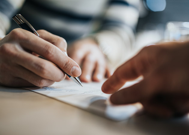 Hand hält einen Stift über einem Blatt Papier. (Quelle: iStock | skynesher) Hand hält einen Stift über einem Blatt Papier.